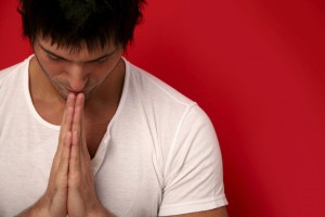 Person with hands in prayer at heart