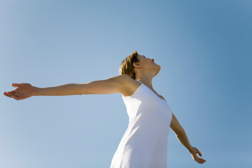 Woman with outstretched arms, looking up, low angle view